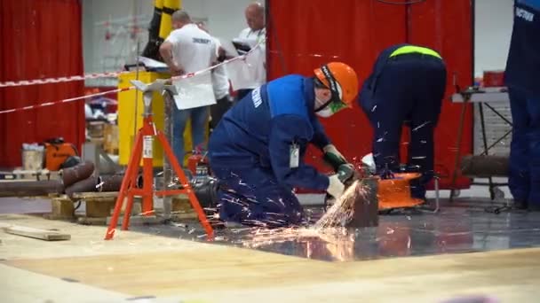 ロシア 8月07 2019 工場の背景に研削盤で金属パイプを研磨する1人の男 労働者は安全上の注意を観察し 青い制服を着用し 保護手袋を着用し 頭の上に赤いヘルメット 火花から覆われたマスク — ストック動画