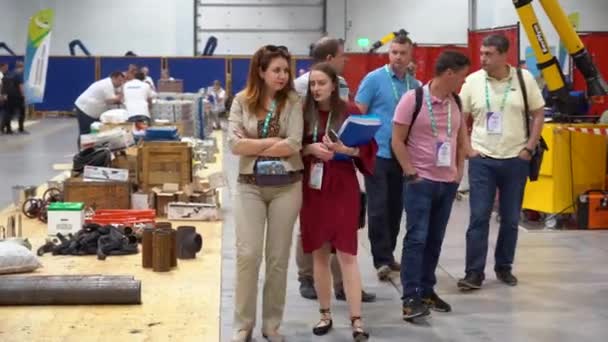 2019年8月7日 一群手持徽章的人在工具 金属丝的背景下行走 检查工厂的工作过程和安全设备 女商人彼此交谈 — 图库视频影像