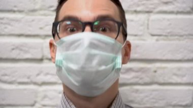 Virüsten koruyucu tıbbi maske takan gri tişörtlü, beyaz tuğlalı bir arka planda başını aşağı yukarı sallayarak evet diyor. Onay jesti ve kabul eder.