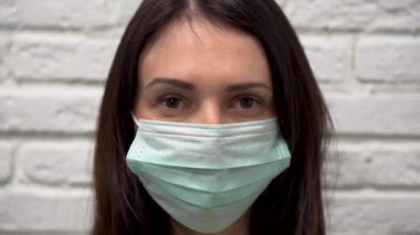 Kahverengi gözlü, uzun saçlı, yüzünde koruyucu turkuaz maske takan hoş esmer bir kadın. Kız şaşırdı ve beyaz tuğladan bir duvara doğru gülümsedi..