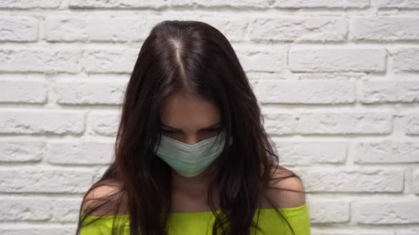 얼굴을 보호하는 의료용 마스크를 매력적 머리의 가까이 내려다보고 소녀가 고개를 — 비디오