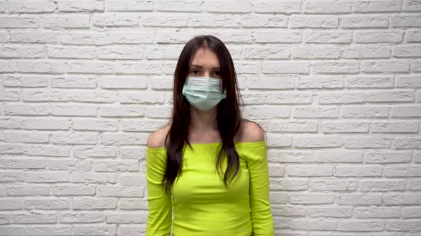 Yeşil Ceketli Uzun Kahverengi Saçlı Koruyucu Tıbbi Maskeli Beyaz Duvarlı — Stok video