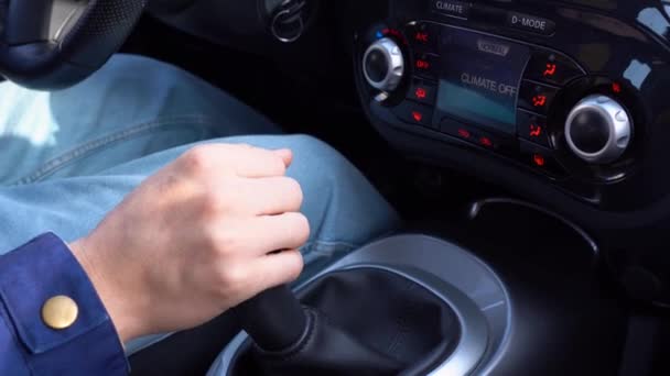 ブルーのジャケットに身を包んだドライバーの手が 美しい車の中でマニュアルギアをシフトアップしている 男は自動車とスイッチギアを制御し 様々なギアを回します 1速から2速から3速にギアを交換する男性 — ストック動画