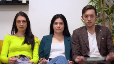 Bir adam maske takıyor, sonra mavi ceketli bir kız, sonra yeşil kazaklı üçüncü kadın. İnsanlar aynı anda oturup turkuaz, siyah ve pembe koruyucu tıbbi maskeler takıyorlar. Covid 19 virüs koruma kavramı.