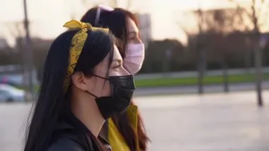 Sarı bantlı, uzun saçlı birkaç tatlı İspanyol kız pembe ve siyah tıbbi koruyucu maskeler takıyor, yürüyor, konuşuyor ve gün batımında sokaklarda zevkle vakit geçiriyorlar. Coronavirus covid-19 virüsü tehdidi nedeniyle kilitlenin.
