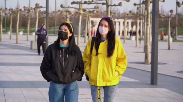 两名妇女在检疫期间不待在家里享受生活 穿着黑黄相间夹克的女孩戴着护目镜 彼此相爱地看着对方在城市公园里慢动作 — 图库视频影像