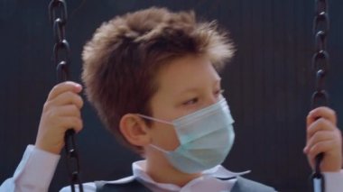 Beyaz gömlekli şirin bir çocuk, maske takıyor, üzgün ve yavaş salıncakta sallanıyor, yeni arkadaşlar arıyor. Elleri paslı metal zinciri tutuyor. Hiç kimse onunla oynamak istemiyor. Etkilenmiş konsept.