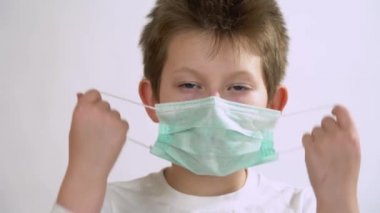 Uzun kollu, mavi gözlü bir doktor olarak genç bir çocuk çıkar ve yüzüne koruyucu koruyucu maske tak. 2019-NCoV enfeksiyonu olduğundan şüphelenilen beyaz bir çocuk. İzole edilmiş beyaz arkaplan.