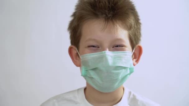 小男孩 金黄色的短发 戴着绿色的防护医疗面具 微笑着走近 快乐的孩子戴着面部呼吸口罩 享受着在日冕病毒和流感爆发期间的生活 回收概念 — 图库视频影像