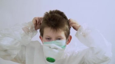 Kısa sarı saçlı çekici beyaz adam koruyucu bir takım elbise giyer ve tıbbi maske takar. Corona virüsünden maske takar, gözlük takar ve beyaz arka planda izole edilmiş bir başlık takar..