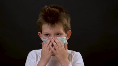 Beyaz tişörtlü güzel beyaz adam yüzüne koruyucu bir tıbbi maske takar, başını soldan sağa sallar ve siyah arka planda can sıkıntısından dans eder. Hasta çocuğun portresi