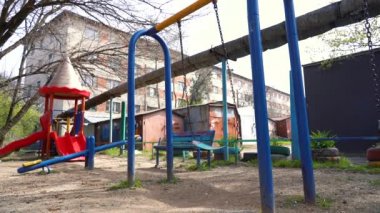 Coronavirus covid-19 virüsü tehdidi nedeniyle şehir merkezindeki çocuk parkında yalnız mavi salıncaklar sallanıyor. Olağanüstü hal. Ağır çekim. Rusya 'da yaz.
