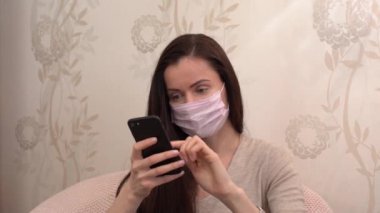 Esmer saçlı, koruyucu pembe maskeli, bej bluzlu güzel bir genç kız. Kanepede oturur, rahatlar, siyah akıllı telefon ya da cep telefonu kullanır. Bir şey izler ya da kısa mesaj atar.