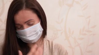 Hasta, beyaz, bej formalı, mavi koruyucu tıbbi maske takan, hasta, beyaz, Rus esmer kadın ağzını eliyle kapayıp, öksürerek kapatıyor. Koronavirüs covid-19 virüsü tarafından karantinada izolasyon