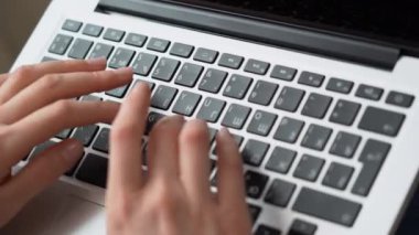 Serbest çalışan genç kız dizüstü bilgisayarı yakından kullanıyor. Not defteri klavyesinde yazı yazan ince elli bir kadın. Kadın e-postalara cevap veriyor, internette sörf yapıyor. Pandemik karantina günlerinde uzak ev işleri. Üst görünüm.