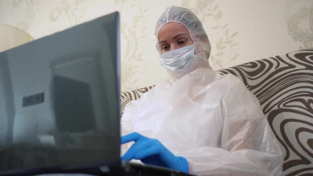 Fiatal Nővér Fehér Védőruhát Orvosi Maszkot Kék Kesztyűt Visel Laptopot — Stock videók