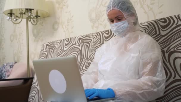 Sanitäter Sitzen Weißen Schutzanzug Auf Dem Sofa Medizinische Gesichtsmaske Blaue — Stockvideo