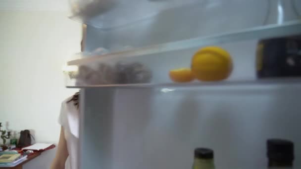 Красивая Белая Девушка Длинными Каштановыми Волосами Закрывает Дверь Холодильника Выпучив — стоковое видео