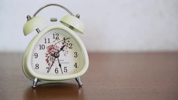 Réveil vintage blanc avec cloches debout sur une table en bois brun, sur fond flou fermer. Vieille cloche classique vers 13h28 La seconde main se déplace rapidement sur le cadran de l'horloge, accéléré 
