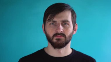 Kahverengi saçlı, siyah gömlekli, yüzünde koruyucu tıbbi maske takan mavi duvarlı, güzel, beyaz bir adam. Covid-19 Coronavirus Koruma Konsepti.