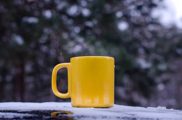 ağaçların bulanık arka planda kar üzerinde duran izole Sarı fincan