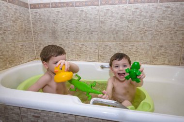 İki küçük ikiz çocuklar tarafından banyo su ile birlikte oyun