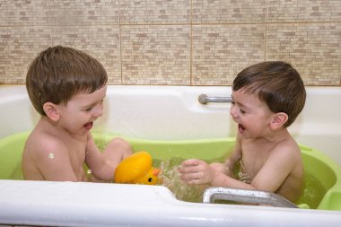 İki küçük ikiz çocuklar tarafından banyo su ile birlikte oyun