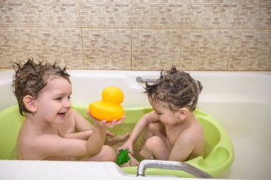 İki küçük ikiz çocuklar tarafından banyo su ile birlikte oyun