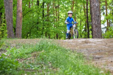 Mutlu komik küçük çocuk çocuk renkli yağmurluk onun ilk soğuk günde ormanda Bisiklete binmek. Çocuklar açık havada için etkin boş. Çocukluk kavramı
