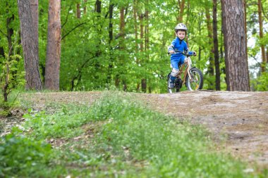 Mutlu komik küçük çocuk çocuk renkli yağmurluk onun ilk soğuk günde ormanda Bisiklete binmek. Çocuklar açık havada için etkin boş. Çocukluk kavramı