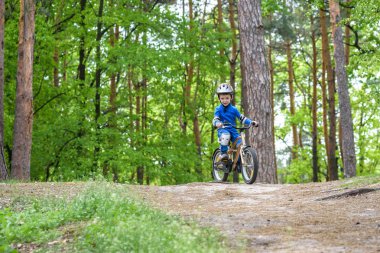 Mutlu komik küçük çocuk çocuk renkli yağmurluk onun ilk soğuk günde ormanda Bisiklete binmek. Çocuklar açık havada için etkin boş. Çocukluk kavramı