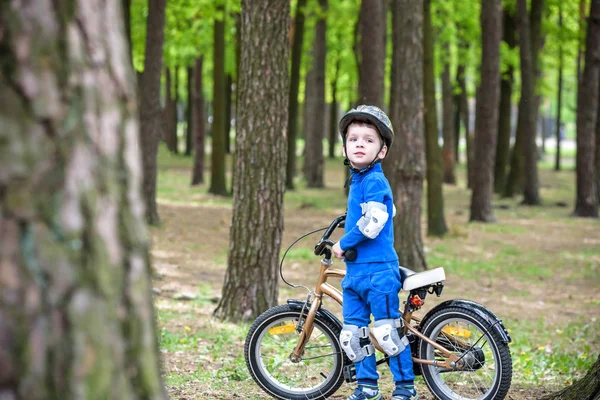 Szczęśliwy chłopiec 4 lat zabawy w lesie jesienią lub latem z rowerem na upadek piękny wiosenny dzień. Aktywne dziecko co sportowe. Bezpieczeństwa, aktywny wypoczynek dla dzieci koncepcja — Zdjęcie stockowe