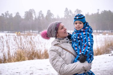 mutlu kadın ve çocuk kışın kar altında kucaklayan