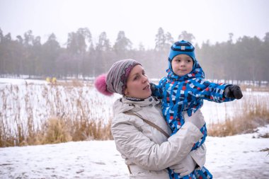 mutlu kadın ve çocuk kışın kar altında kucaklayan