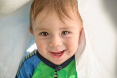 doğrudan kameraya bakarak battaniye mutlu çocuk altında yüzü gülen çocuk