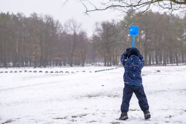 Çocuk çocuk açık havada kar yağışı sırasında renkli giysiler içinde kış portresi. Soğuk karlı günlerde çocukları ile etkin outoors eğlence. Eğleniyor mutlu yürümeye başlayan çocuk ormanda kar