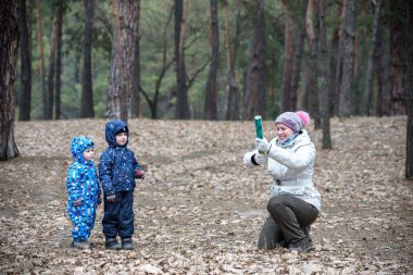 Anneleri ile birlikte sonbahar orman oynayan iki küçük kardeş. Anne kuyu kullanacak