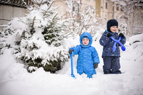 Kids and a lot of snow. playing outdoors in winter near home. two happy smiling brothers. — Stock Photo, Image