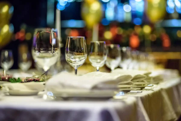 Bicchieri, forchette, coltelli, tovaglioli e fiori decorativi su un tavolo servito per cena in un accogliente ristorante . — Foto Stock