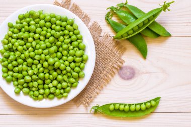 Ahşap arka plan, üstten görünüm veya düz beyaz kase yeşil bezelye 