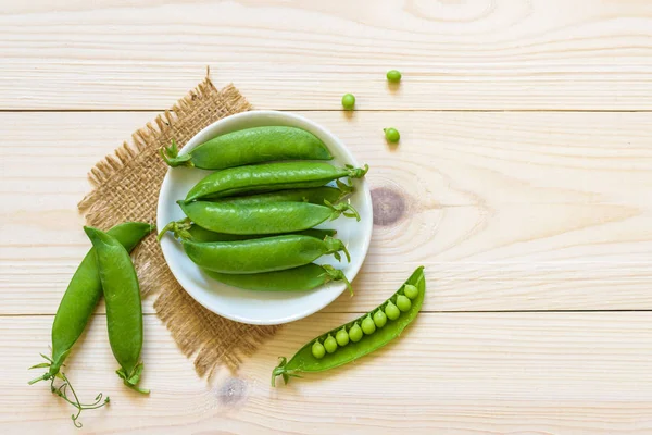 Gröna ärter i skål med ovanifrån på rustika trä bakgrund med c — Stockfoto