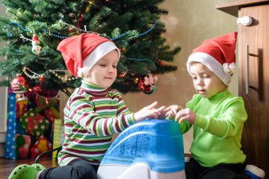 x-mas için bekleyen çalışma nemlendirici ile oynayan iki sevimli çocuklar