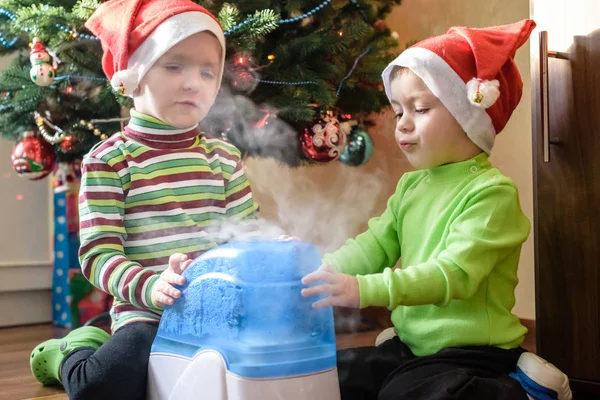 x-mas için bekleyen çalışma nemlendirici ile oynayan iki sevimli çocuklar