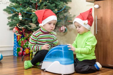 x-mas için bekleyen çalışma nemlendirici ile oynayan iki sevimli çocuklar