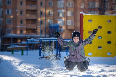 Karda atlama çocuk. Mutlu bir çocukluk açık havada kış şehirde yürüyüş. Çocuk gülen ve having fun.