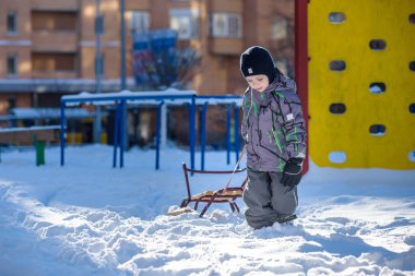 Açık havada kış şehirde yürüyüş çocuk mutlu onun kızak sürükler. Çocuk gülen ve having fun.
