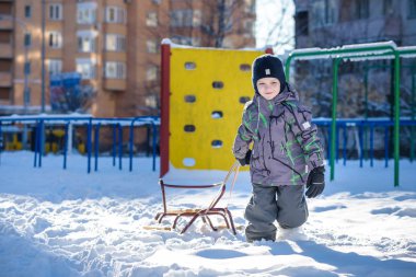 Açık havada kış şehirde yürüyüş çocuk mutlu onun kızak sürükler. Çocuk gülen ve having fun.