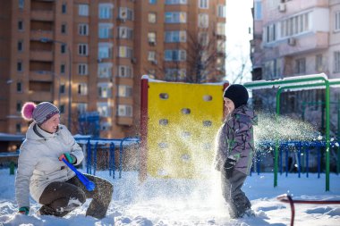 Anne ve oğlu güzel kış günü açık havada, oynamaktan zevk şehirde kar