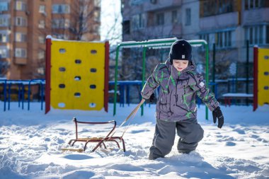 Açık havada kış şehirde yürüyüş çocuk mutlu onun kızak sürükler. Çocuk gülen ve having fun.