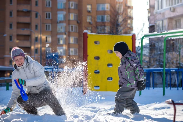 Mère et son fils profitent d'une belle journée d'hiver en plein air, jouant avec la neige en ville — Photo